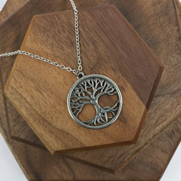A silver Amethyst Celtic knot tree of life necklace on a wooden table.