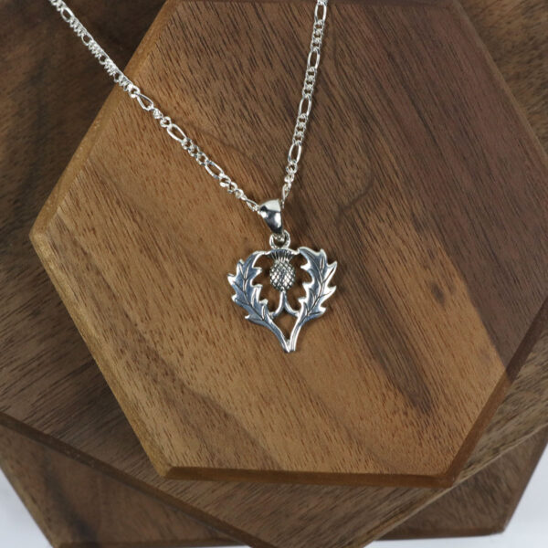 A silver Scottish Thistle Necklace with a heart on it.