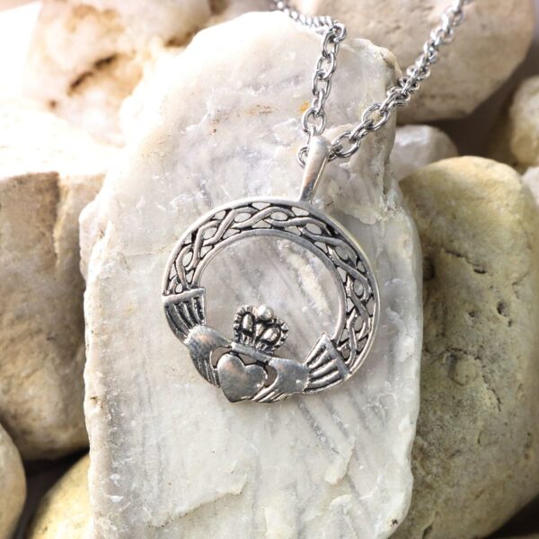 A silver claddagh necklace with a heart on it, featuring Celtic Knot Emerald Earrings.
