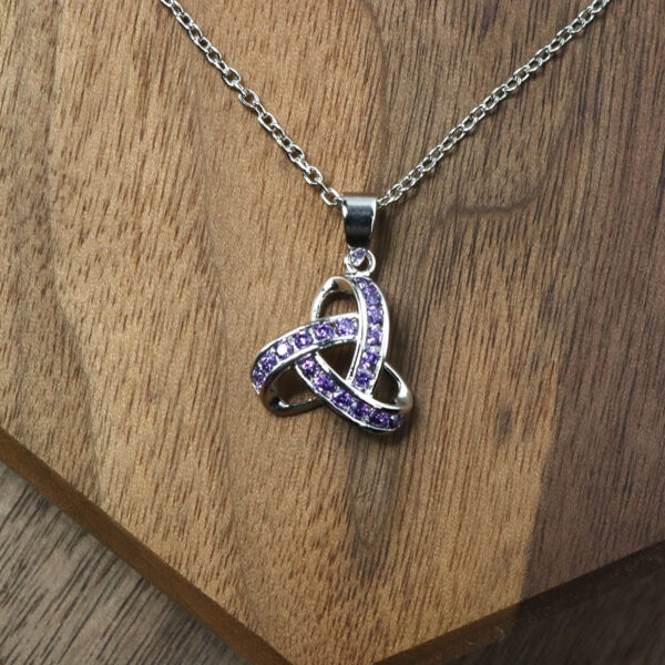 An Amethyst Celtic Knot Necklace displayed on a wooden table.