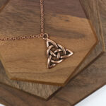 An Amethyst Celtic Knot Necklace on a wooden table.