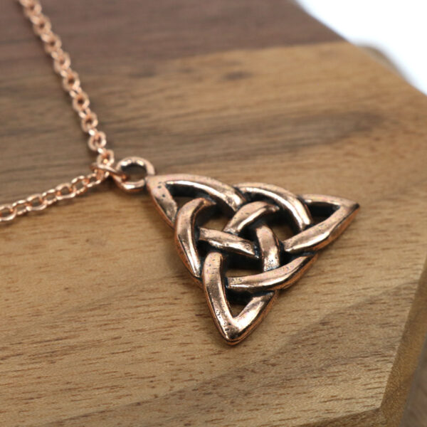 An Amethyst Celtic Knot Necklace on a wooden table.