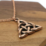 An Amethyst Celtic Knot Necklace on a wooden table.