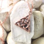 Celtic Knot Emerald Earrings elegantly displayed on a rock.