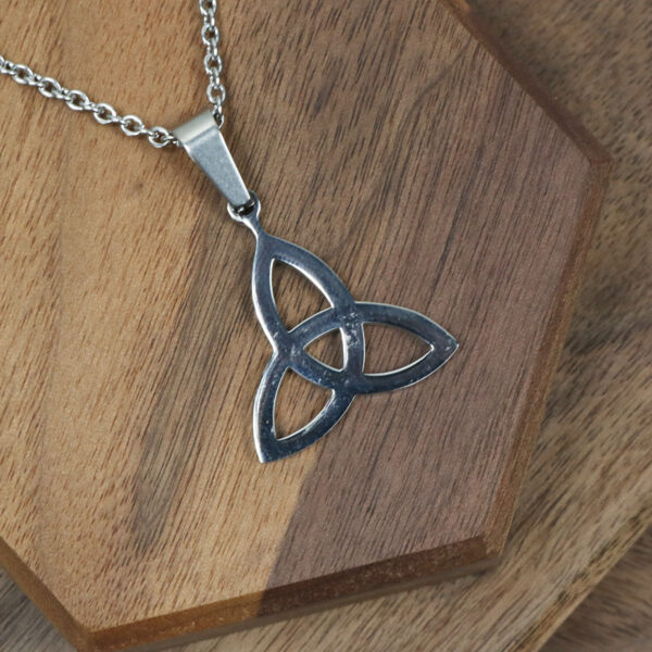 An Amethyst Celtic Knot Necklace elegantly displayed on a wooden table.