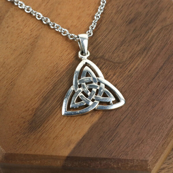 A sterling silver Amethyst Celtic Knot necklace featuring a beautiful amethyst pendant, showcased on a rustic wooden table.