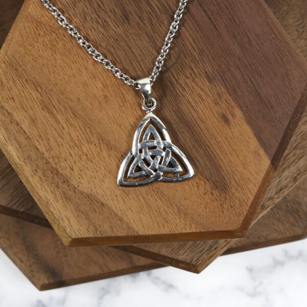 An Amethyst Celtic Knot Necklace adorned with an elegant amethyst gemstone on a wooden table.