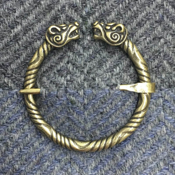 A bronze bracelet with two wolf heads on it.