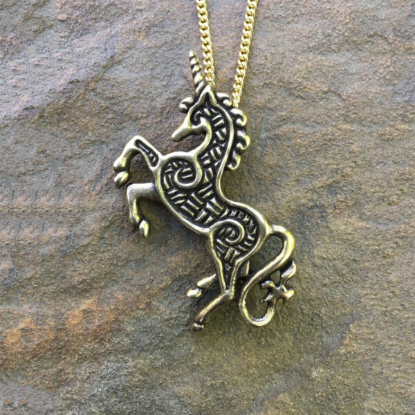 A Celtic Unicorn Pendant on a rock.