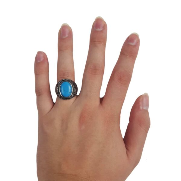 A woman's hand holding a Spiral Turquoise Stainless Steel Ring.