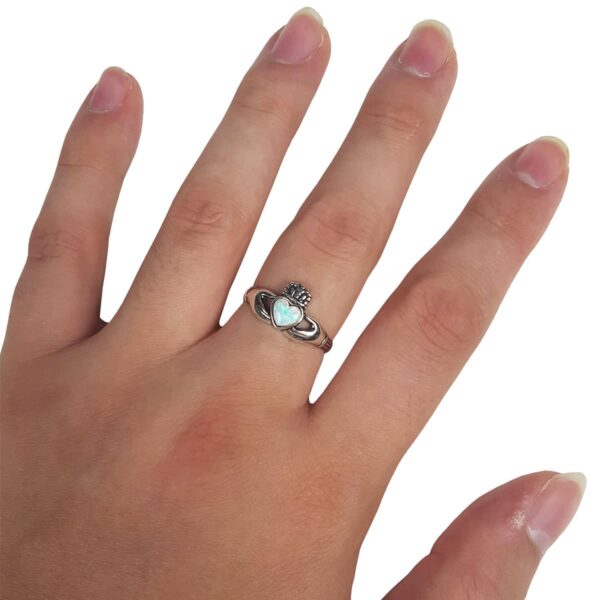 A hand with an Opal Claddagh Ring.