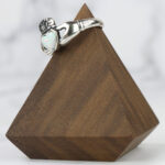 A Two Tone Eternity Knot Band on a wooden base with a woven band.