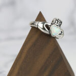 A silver claddagh ring with a Two Tone Eternity Knot Band and an opal heart.