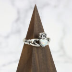 A Two Tone Eternity Knot Band claddagh ring with a sterling silver and opal heart.