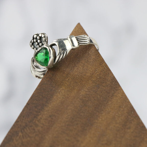 A large claddagh ring with an emerald stone, adorned with a Large Celtic Knot Spinner Ring.