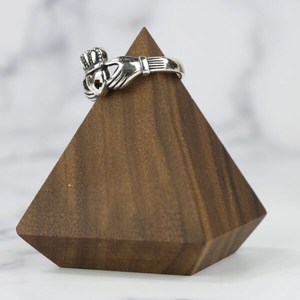 A wooden pyramid adorned with a claddagh ring featuring a Two Tone Eternity Knot Band.