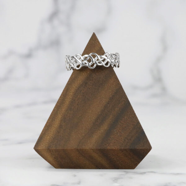 A wooden triangle with a diamond ring and Tangled Celtic Knot Ring on it.