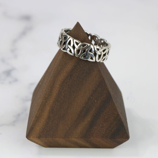 A Large Celtic Knot Spinner Ring sits on top of a wooden pyramid.