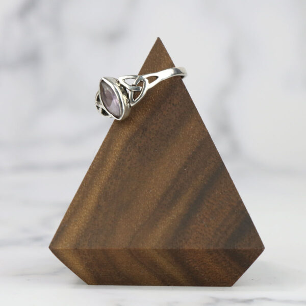 A wooden triangle with a ring on it featuring a Two Tone Eternity Knot Band woven band.