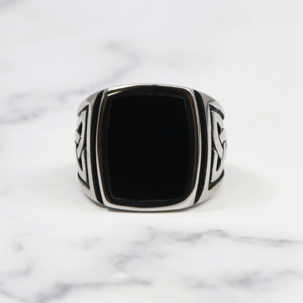 A Black Onyx Stainless Steel Triquetra Ring on a marble table.