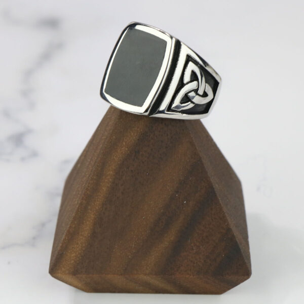 A Black Onyx Stainless Steel Triquetra Ring with a Black Onyx stone on top of a wooden stand.