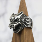 A silver Dire Wolf Stainless Steel Ring on a wooden base.