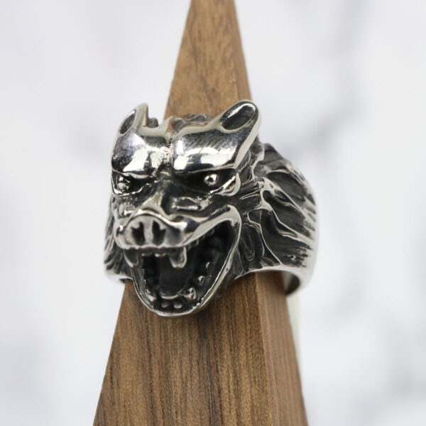 A silver Dire Wolf Stainless Steel Ring on a wooden base.