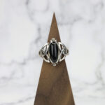 A Black Onyx Trinity Celtic Knot Ring on a Celtic knot wooden base.