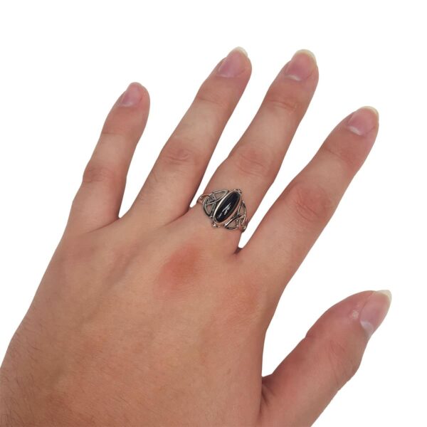 A woman's hand holding a Black Onyx Trinity Celtic Knot Ring.