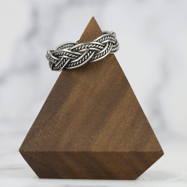 Two Tone Eternity Knot Band ring, beautifully displayed on a wooden stand.