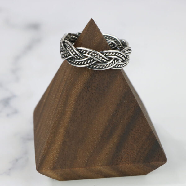 A Two Tone Eternity Knot Band on top of a wooden pyramid.