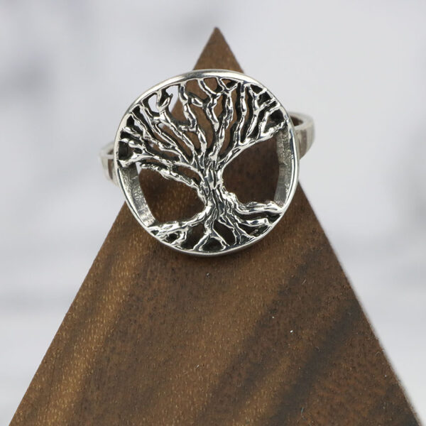 A Tree of Life Sterling Silver Ring sterling silver ring on a wooden base.