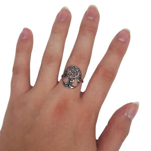 A woman's hand holding a Tree of Life Stainless Steel ring.