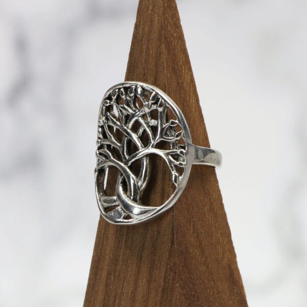 A Tree of Life Stainless Steel Ring on a wooden base.