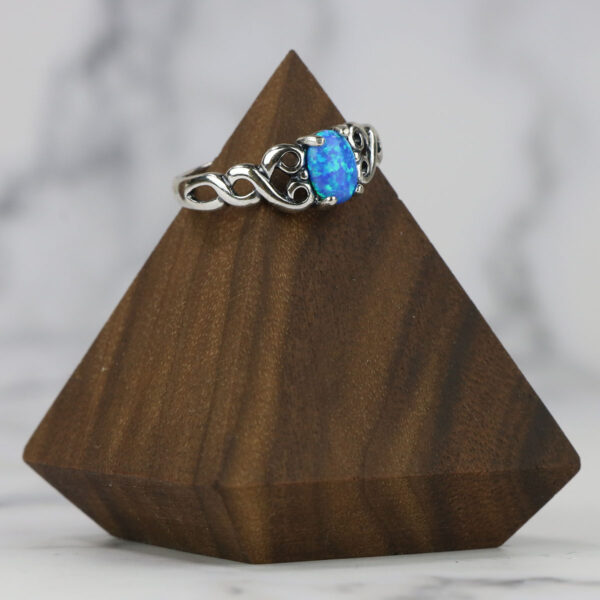 A large blue opal Large Celtic Knot Spinner Ring, sitting on top of a wooden block.