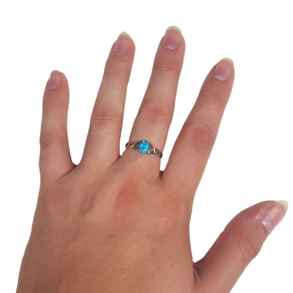 A woman's hand adorned with a Heart Knot Blue Opal Sterling Silver Ring featuring an opal.