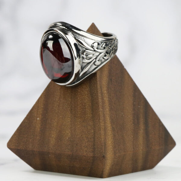 A Dragon's Eye Ring with a red stone on top of a wooden block.