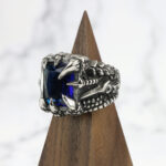 A Dragon Claw Stainless Steel Ring with a blue sapphire.
