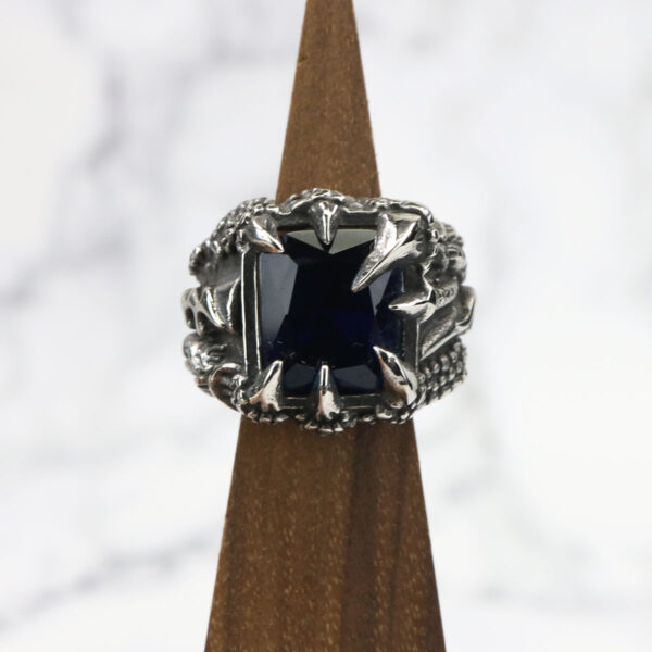 A Dragon Claw Stainless Steel Ring with a blue sapphire on top.