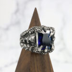 A Dragon Claw Stainless Steel Ring with a blue sapphire stone.