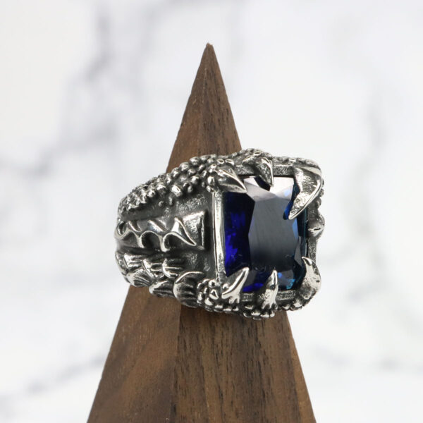 A Dragon Claw Stainless Steel Ring with a blue sapphire stone.