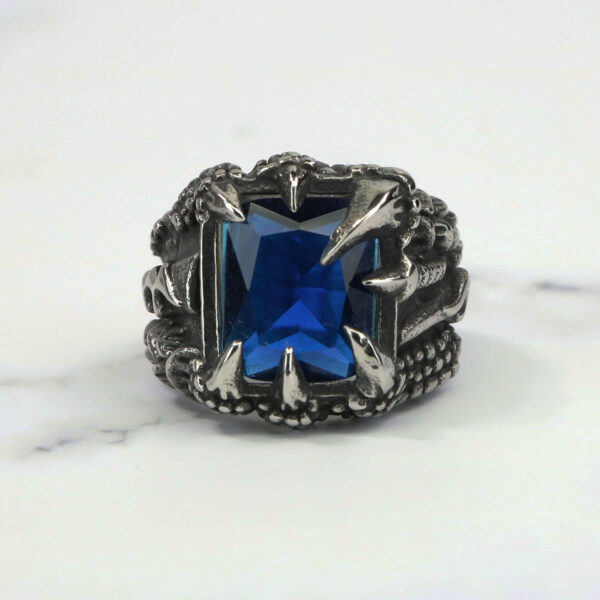 A Dragon Claw Stainless Steel Ring with a blue sapphire.