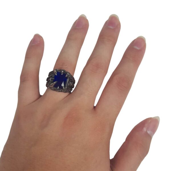 A woman's hand holding a blue sapphire Dragon Claw Stainless Steel Ring.