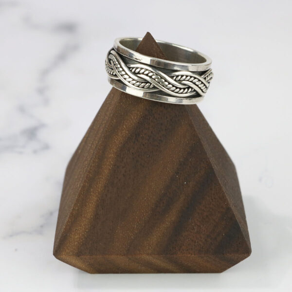 A Large Celtic Knot Spinner Ring sits on top of a wooden stand.