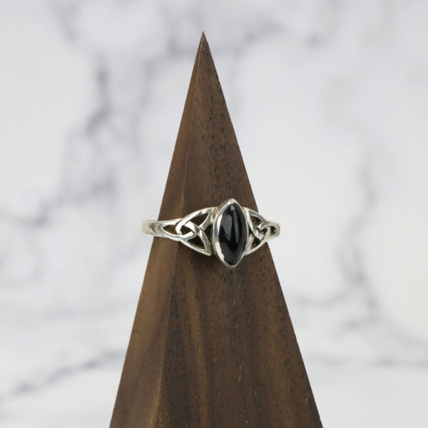 A black onyx ring with a Two Tone Eternity Knot Band, placed on top of a triangle.
