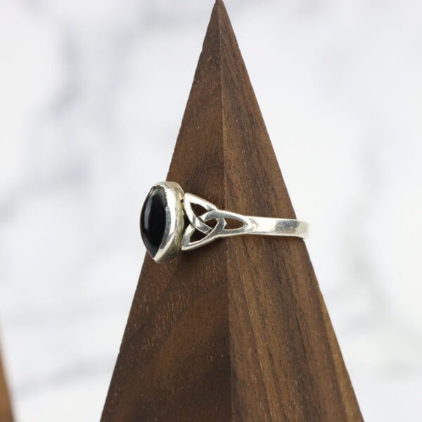 A sterling silver ring with a black onyx stone featuring a Two Tone Eternity Knot Band.