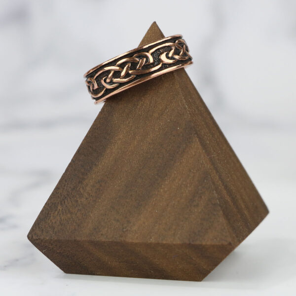 A Copper Celtic Knot Ring on top of a wooden block.