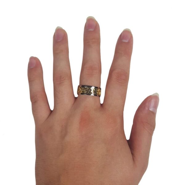 A woman's hand with a Two Tone Triquetra Ring featuring a triquetra design.