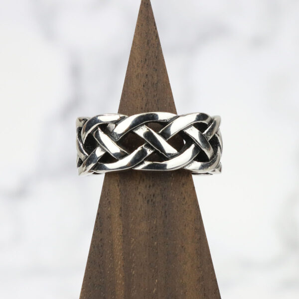 An Interlacing Endless Knot Ring with an endless knot design on top of a wooden base.