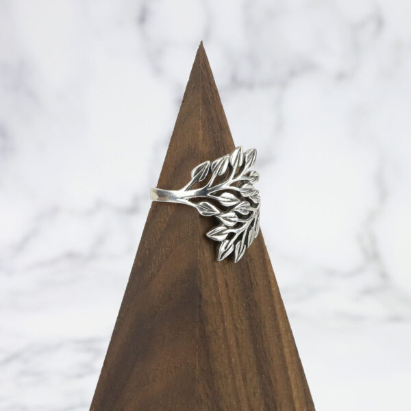 A Two Tone Eternity Knot Band with leaves delicately woven on top, resting on a wooden pyramid.